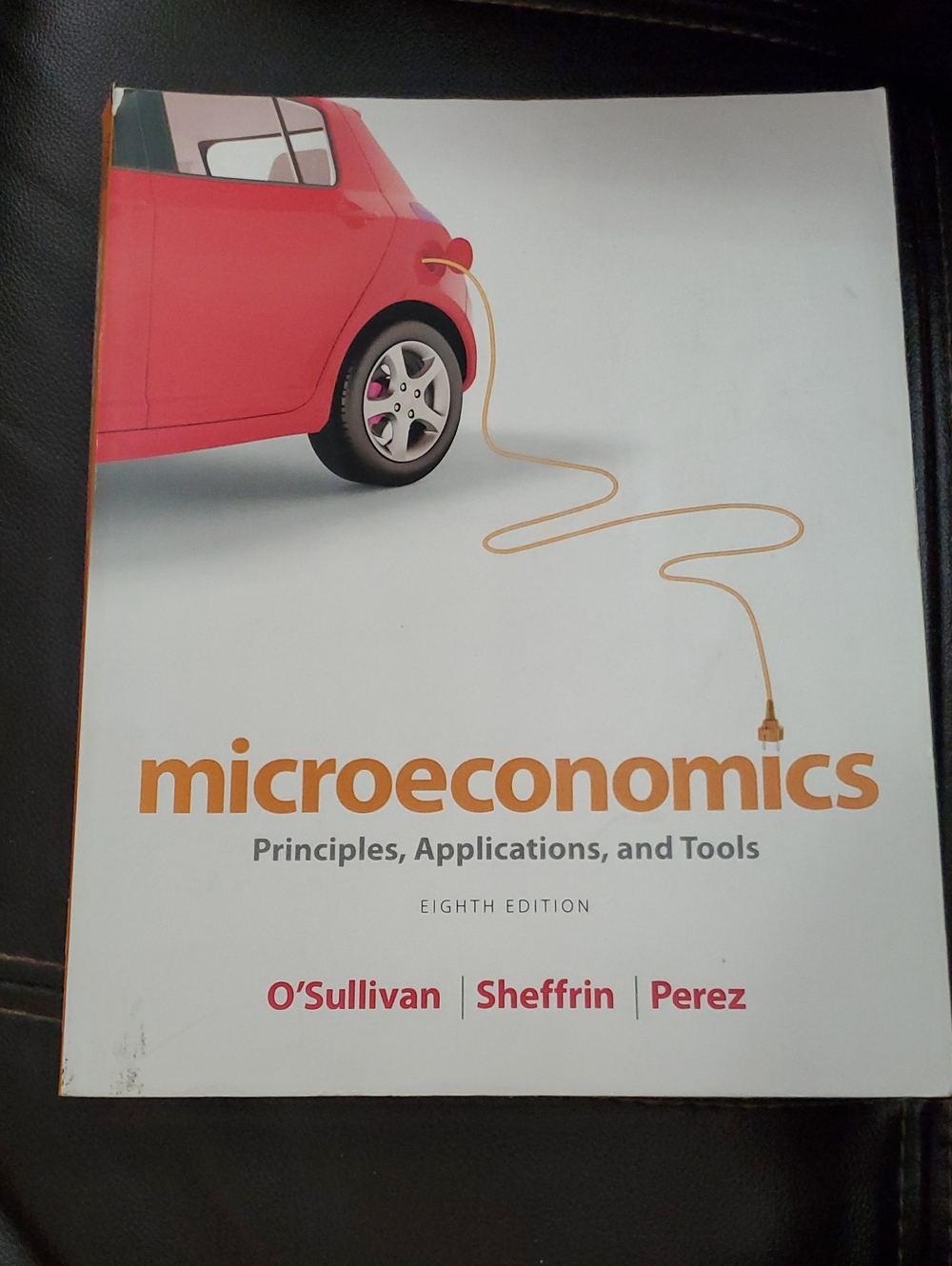 Pearson Microeconomics Textbook with Pink Car and Orange Typography